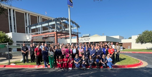 Photo of Hendrick Medical Center Brownwood employees outside hospital near flag pole. 